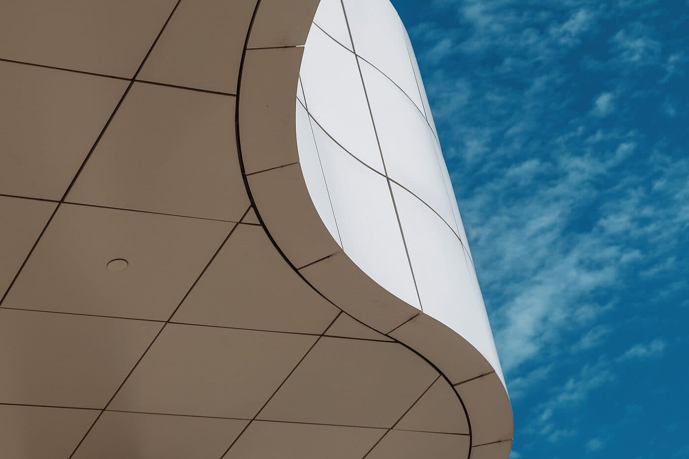 The curved underside of a white canopy against a blue sky