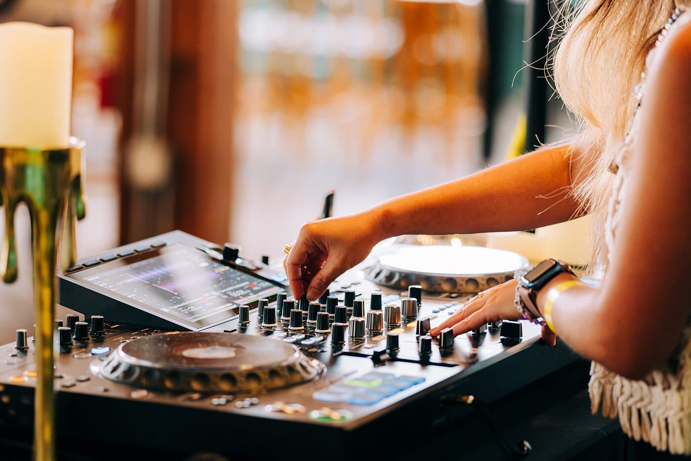 A DJ's hands over a mixer and decks in warm evening light