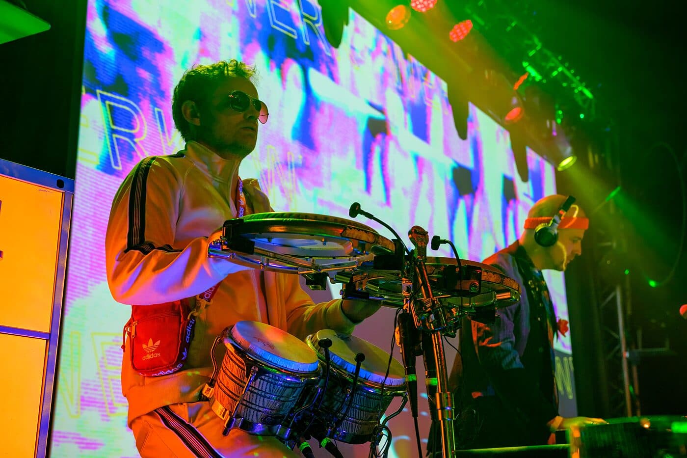 A drummer on stage, washed in green and magenta